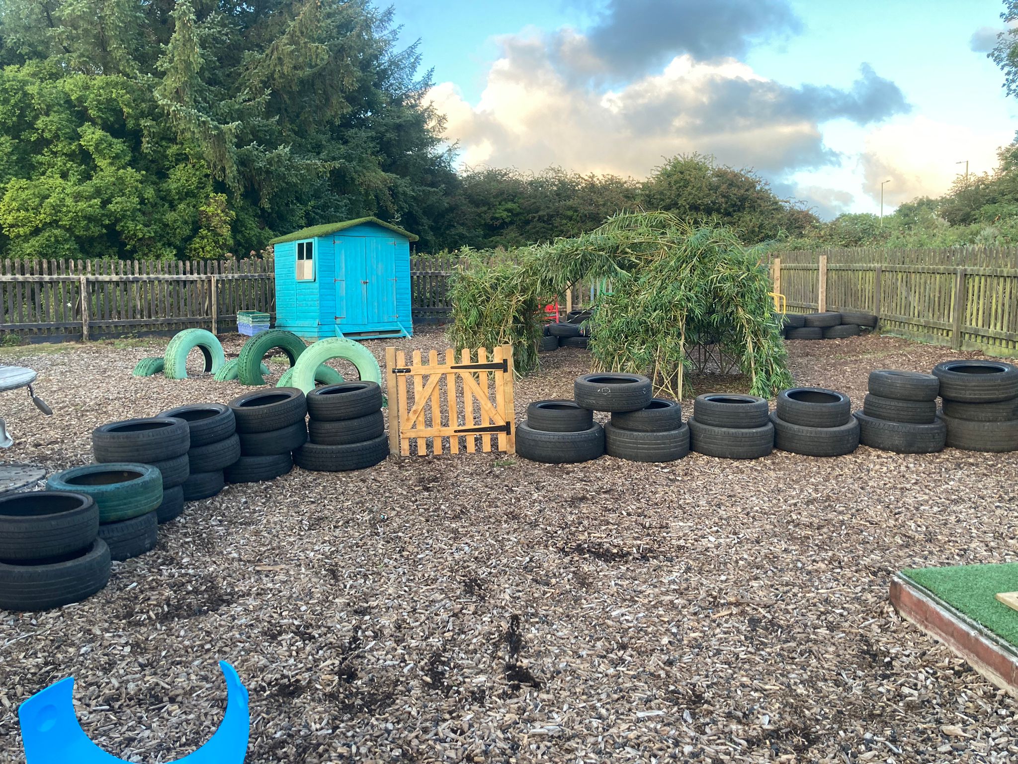 Outside play area for children with bark floor, tyres and a shed